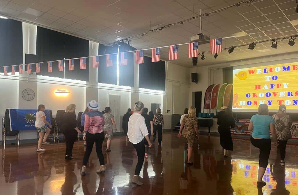 Staff at Hazel Grove High School take part in an American line dancing session in the school hall which is decorated with US flag bunting.