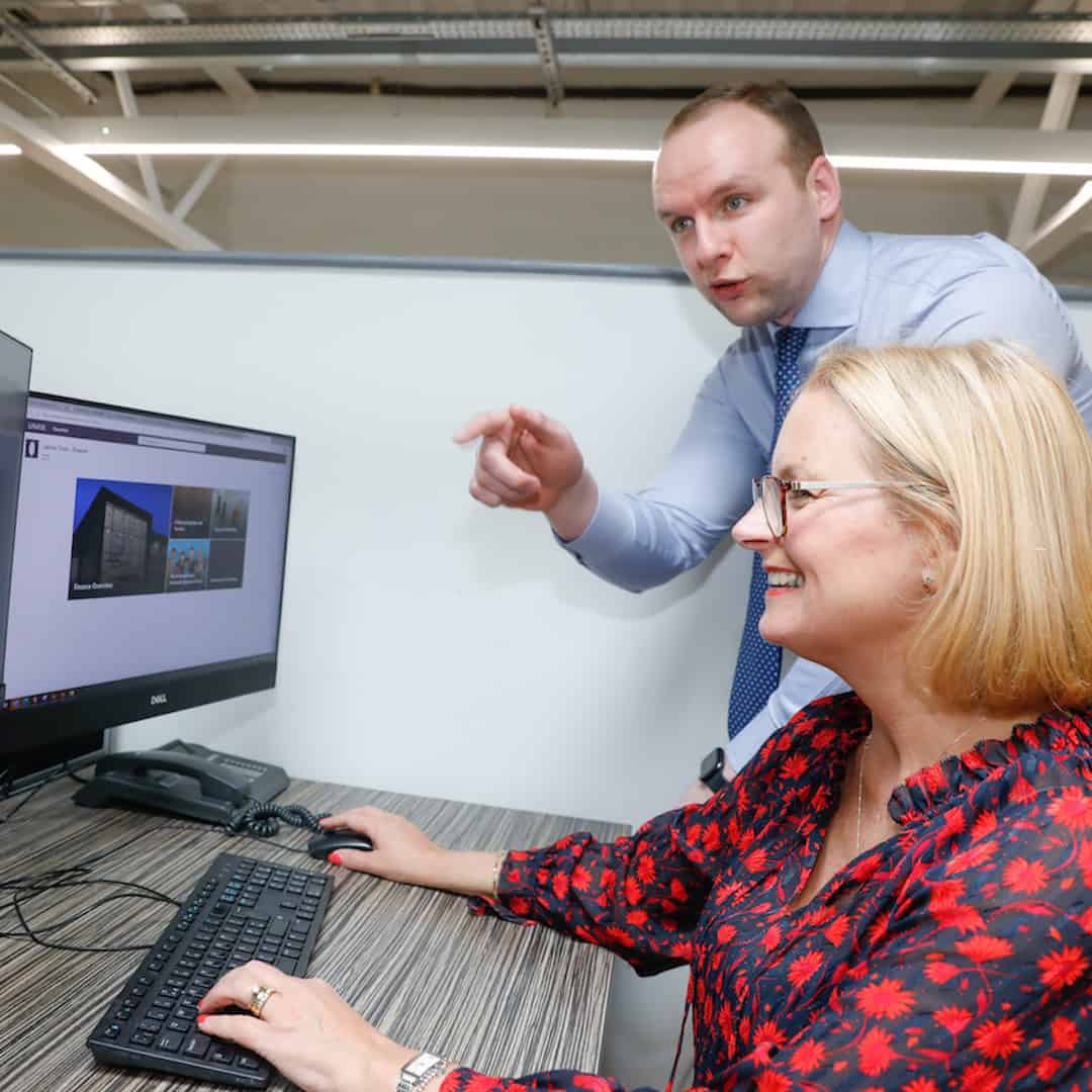 Two members of staff work together on a PC in central services of Laurus Trust.